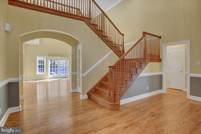 staircase featuring ornamental molding, hardwood / wood-style floors, and a towering ceiling