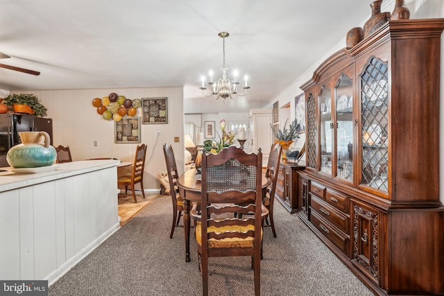 carpeted dining room with ceiling fan with notable chandelier