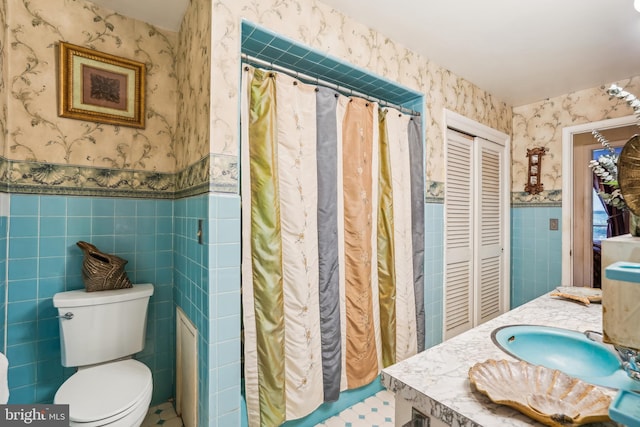 bathroom with toilet, a shower with shower curtain, vanity, and tile walls