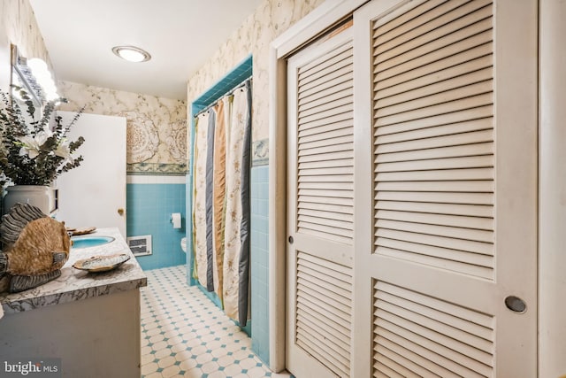 bathroom with tile walls, vanity, and toilet