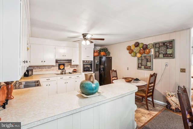 kitchen with black appliances, sink, kitchen peninsula, white cabinetry, and ceiling fan