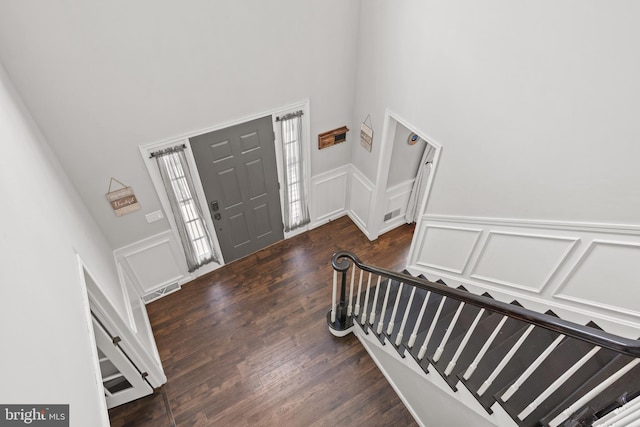 entryway with a towering ceiling and dark wood-type flooring