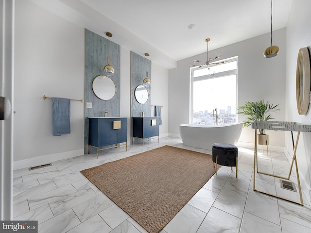 bathroom featuring an inviting chandelier, a tub, and vanity