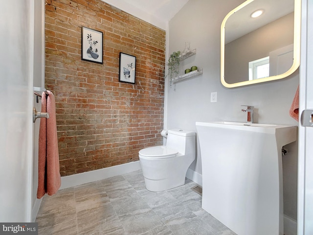 bathroom with toilet and brick wall