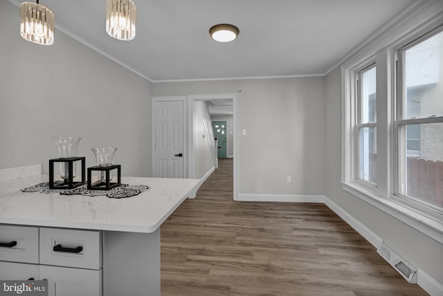 kitchen featuring white cabinets, hardwood / wood-style flooring, decorative light fixtures, and crown molding