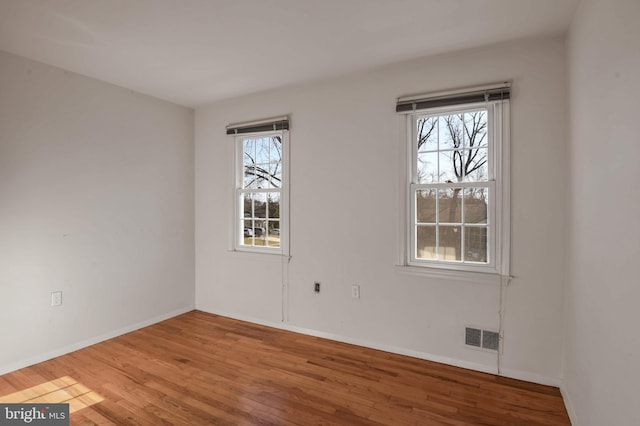 spare room with wood-type flooring and a wealth of natural light