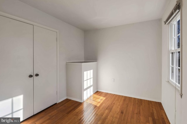 unfurnished bedroom featuring hardwood / wood-style floors and multiple windows