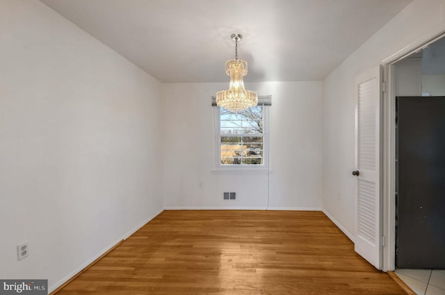 unfurnished dining area featuring hardwood / wood-style floors and a chandelier