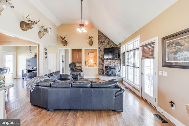 living room featuring a wood stove, high vaulted ceiling, ceiling fan, and light hardwood / wood-style floors