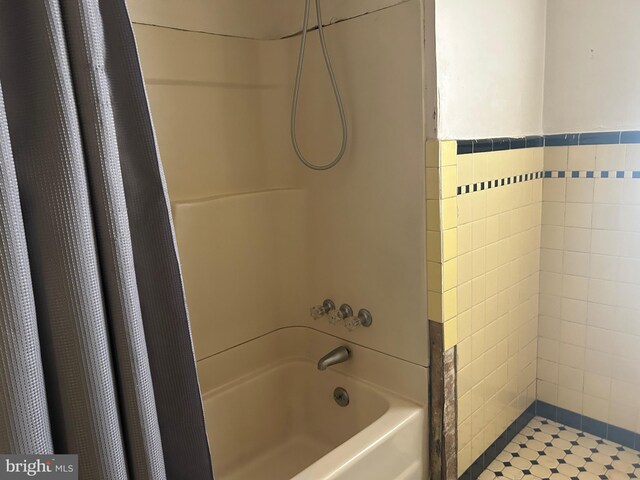 bathroom featuring shower / bathtub combination with curtain and tile walls