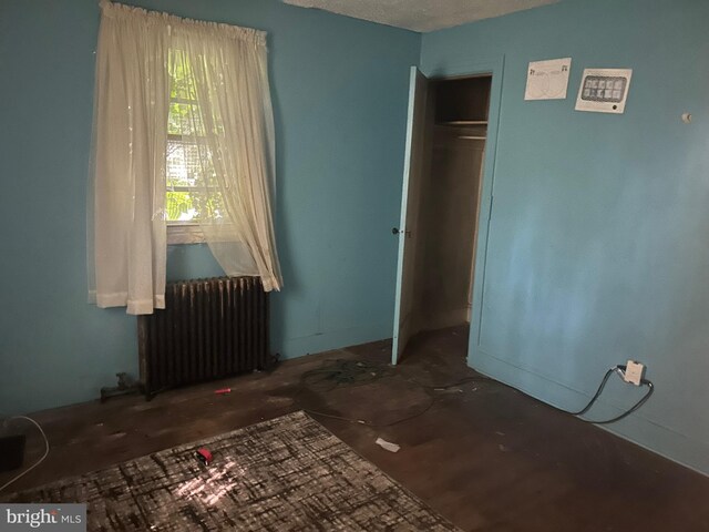 unfurnished bedroom featuring radiator, a textured ceiling, and a closet