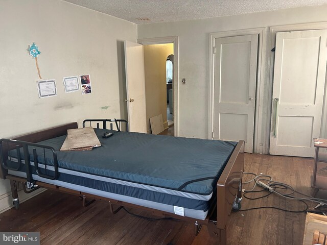 bedroom with dark hardwood / wood-style floors and a textured ceiling