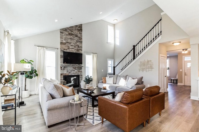 living room with a fireplace, light hardwood / wood-style floors, and high vaulted ceiling