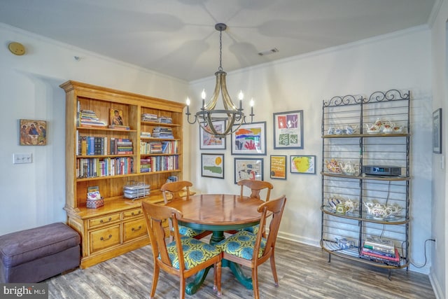 dining room with crown molding, hardwood / wood-style floors, and an inviting chandelier