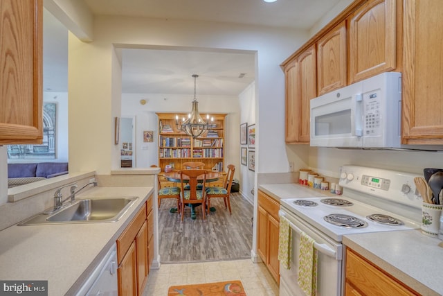 kitchen featuring white appliances, sink, light hardwood / wood-style floors, pendant lighting, and a chandelier