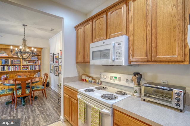 kitchen with white appliances, decorative light fixtures, an inviting chandelier, and light hardwood / wood-style flooring