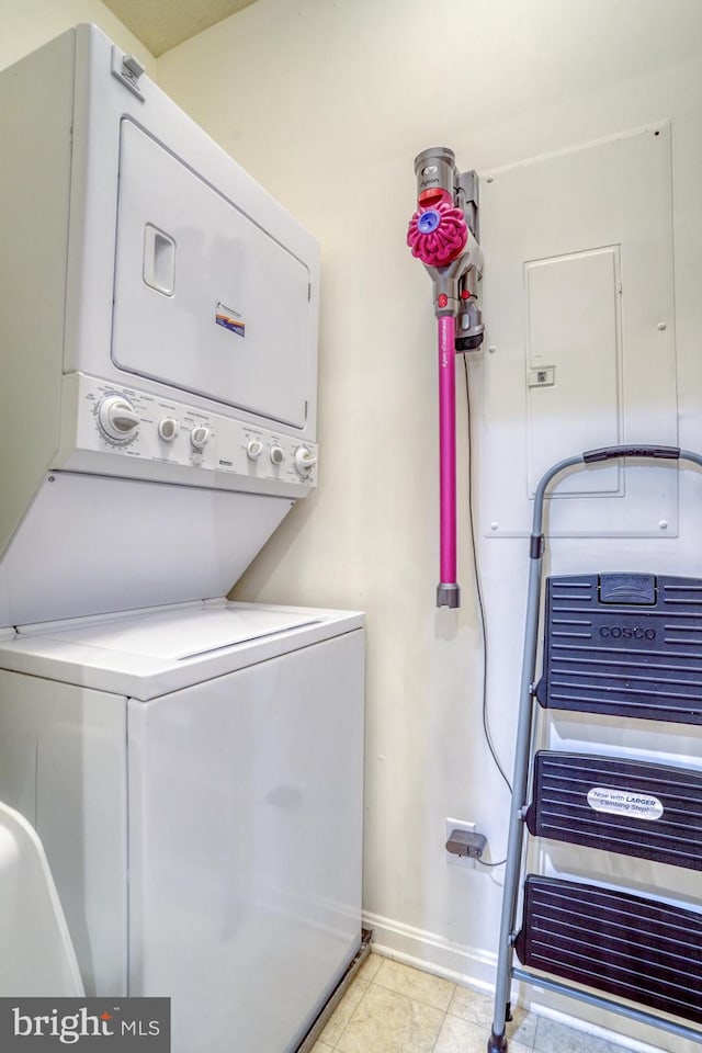 laundry area with stacked washer / dryer and light tile patterned floors