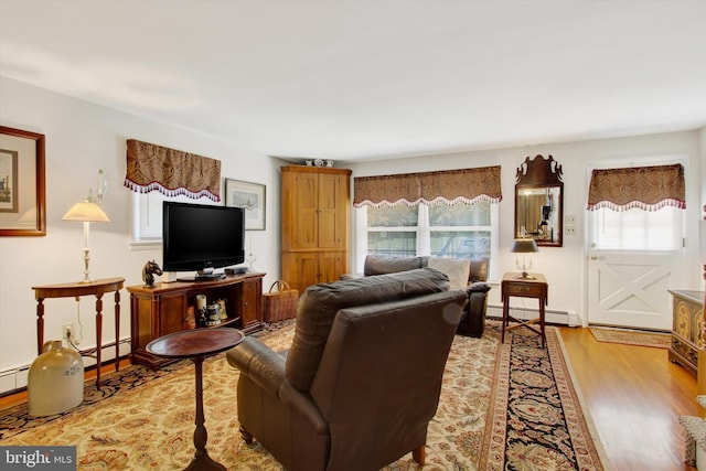 living room with light hardwood / wood-style floors, a healthy amount of sunlight, and baseboard heating