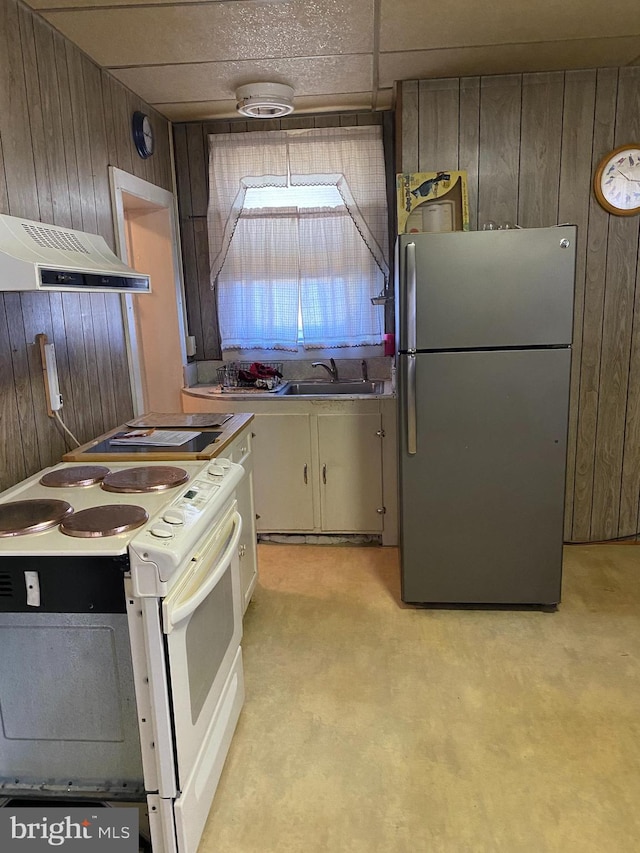 kitchen featuring wooden walls, ventilation hood, white range with electric cooktop, a paneled ceiling, and stainless steel refrigerator