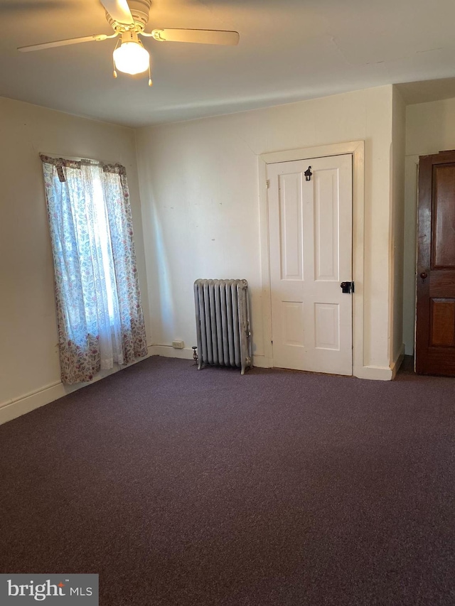 carpeted spare room featuring ceiling fan and radiator