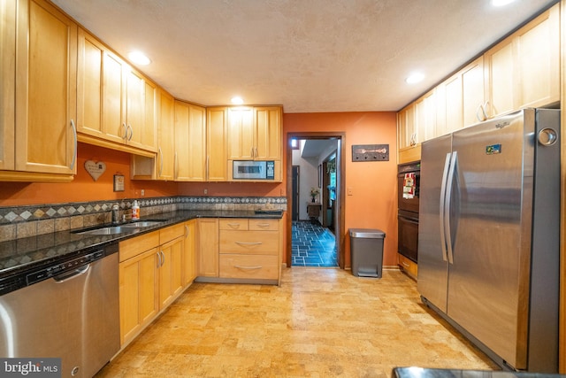 kitchen with stainless steel appliances, dark stone countertops, sink, light hardwood / wood-style floors, and light brown cabinetry