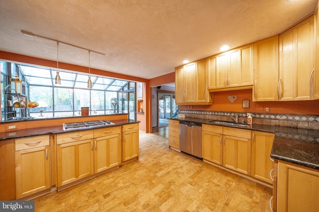 kitchen featuring dark stone countertops, sink, stainless steel appliances, hanging light fixtures, and a textured ceiling