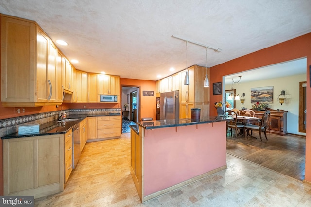 kitchen featuring hanging light fixtures, a kitchen island, light hardwood / wood-style flooring, appliances with stainless steel finishes, and a breakfast bar