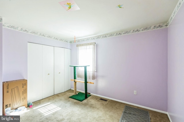 unfurnished bedroom with baseboards, visible vents, carpet floors, and a closet