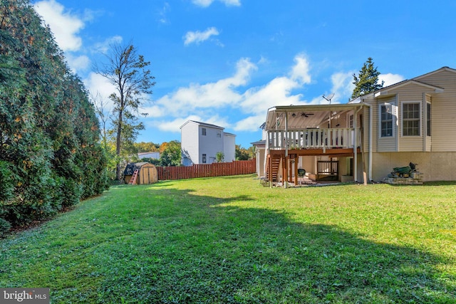 view of yard with a wooden deck, a storage shed, and ceiling fan