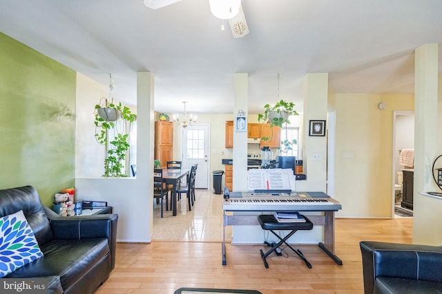 living area featuring light wood finished floors and ceiling fan with notable chandelier