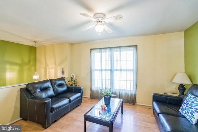 living room with baseboards, light wood-style floors, and ceiling fan