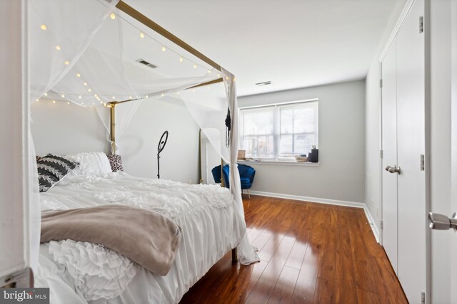 bedroom with visible vents, baseboards, and wood finished floors