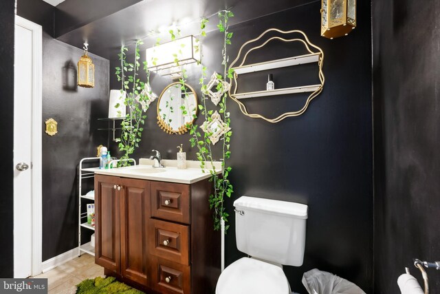 half bathroom featuring tile patterned flooring, toilet, and vanity