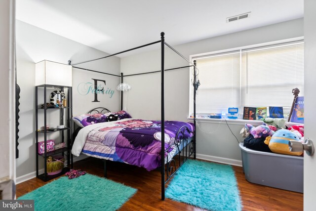 bedroom featuring wood finished floors, visible vents, and baseboards