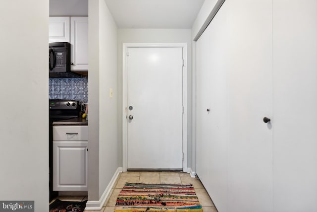 doorway with baseboards and light tile patterned flooring