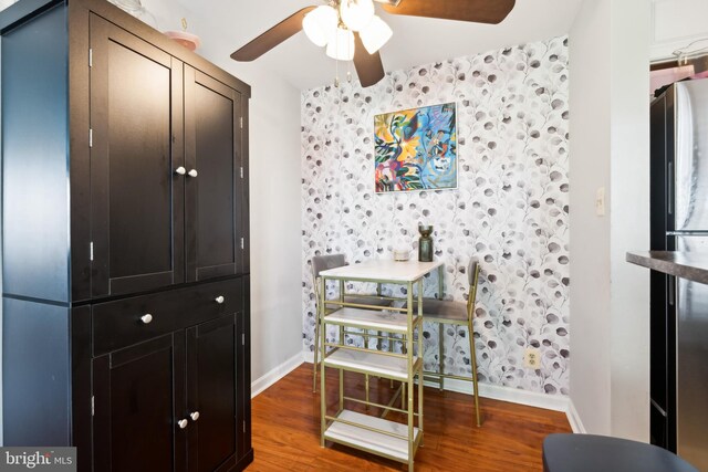 dining room featuring wallpapered walls, baseboards, ceiling fan, and wood finished floors