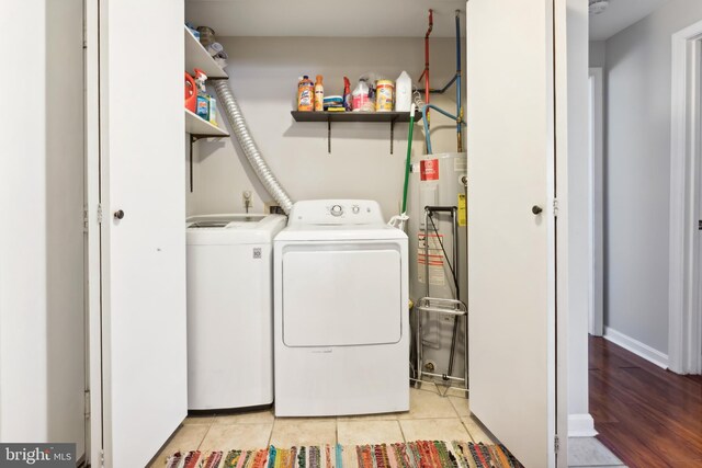 laundry room with light tile patterned flooring, washing machine and dryer, laundry area, and water heater