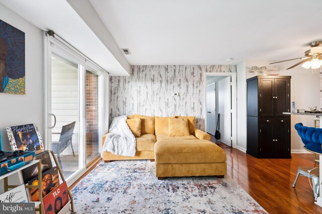 living room featuring wallpapered walls, wood finished floors, a healthy amount of sunlight, and a ceiling fan