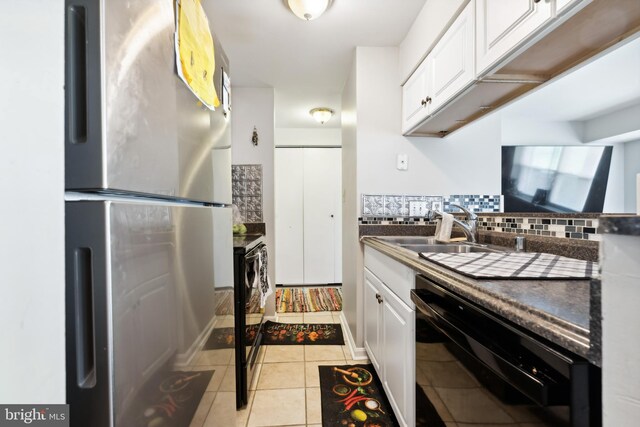 kitchen with white cabinetry, backsplash, black dishwasher, and freestanding refrigerator