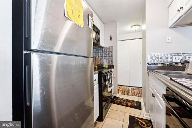 kitchen with light tile patterned floors, decorative backsplash, black appliances, and white cabinets