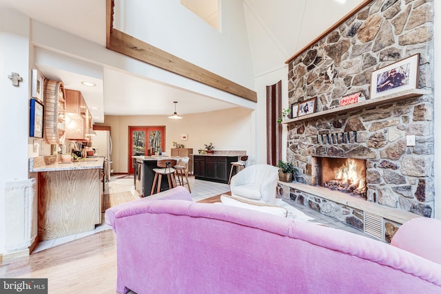 living room with a towering ceiling, bar area, a fireplace, and light hardwood / wood-style floors