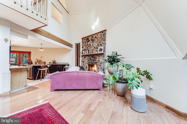 living room with light hardwood / wood-style floors, a towering ceiling, and a fireplace