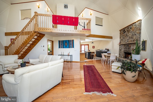 621 Paradise Hts, Oakland, MD 21550 - living area with visible vents, a fireplace, wood finished floors, high vaulted ceiling, and stairs