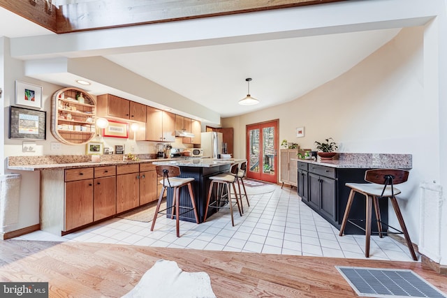 kitchen featuring a breakfast bar area, a kitchen island, and stainless steel refrigerator