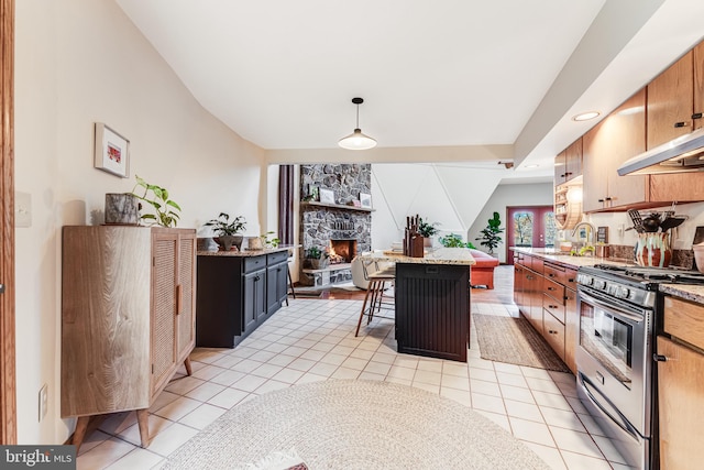 kitchen featuring light tile patterned flooring, a kitchen island, gas stove, decorative light fixtures, and a breakfast bar area