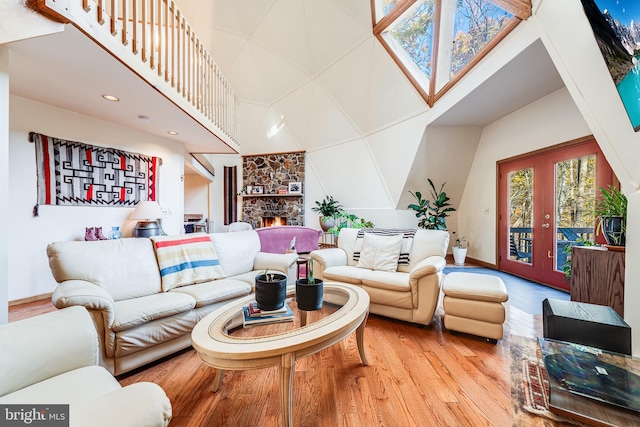 living room with french doors, a stone fireplace, and light wood-type flooring