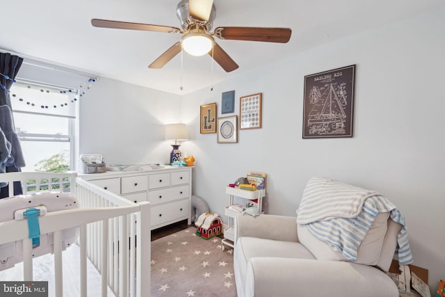 bedroom featuring ceiling fan, a nursery area, and carpet floors