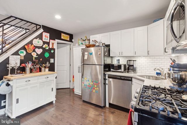 kitchen featuring dark wood-type flooring, white cabinets, sink, backsplash, and appliances with stainless steel finishes