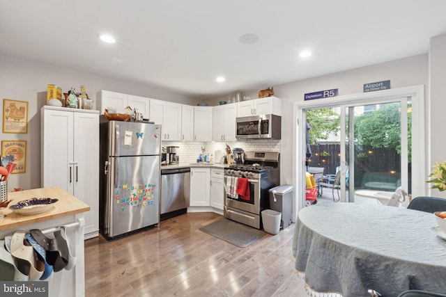 kitchen with white cabinetry, appliances with stainless steel finishes, hardwood / wood-style flooring, and tasteful backsplash