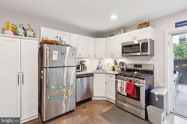 kitchen with white cabinets, decorative backsplash, appliances with stainless steel finishes, and dark wood-type flooring